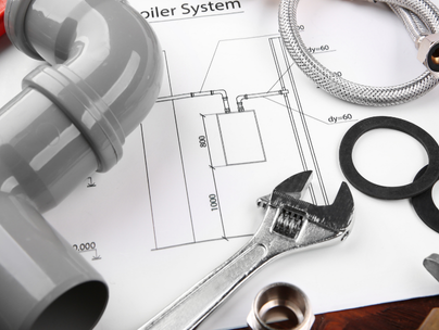 Outils de plomberie, tuyaux et raccords sur un plan d'un système de chaudière.