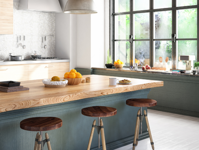 Cuisine avec îlot en bois, tabourets et grande fenêtre donnant sur l'extérieur.