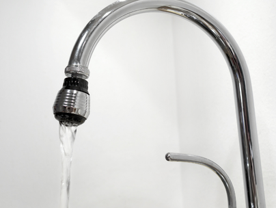 Robinet chromé avec eau qui coule dans un évier.