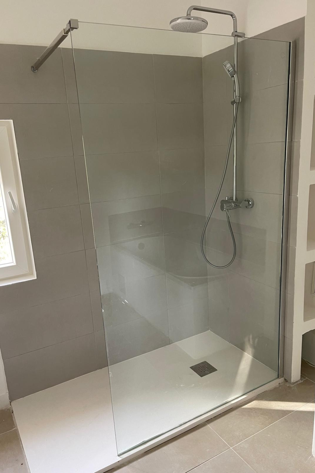 Armoire de cuisine avec des outils et des pièces de plomberie éparpillés sur le sol; un évier et des portes ouvertes.