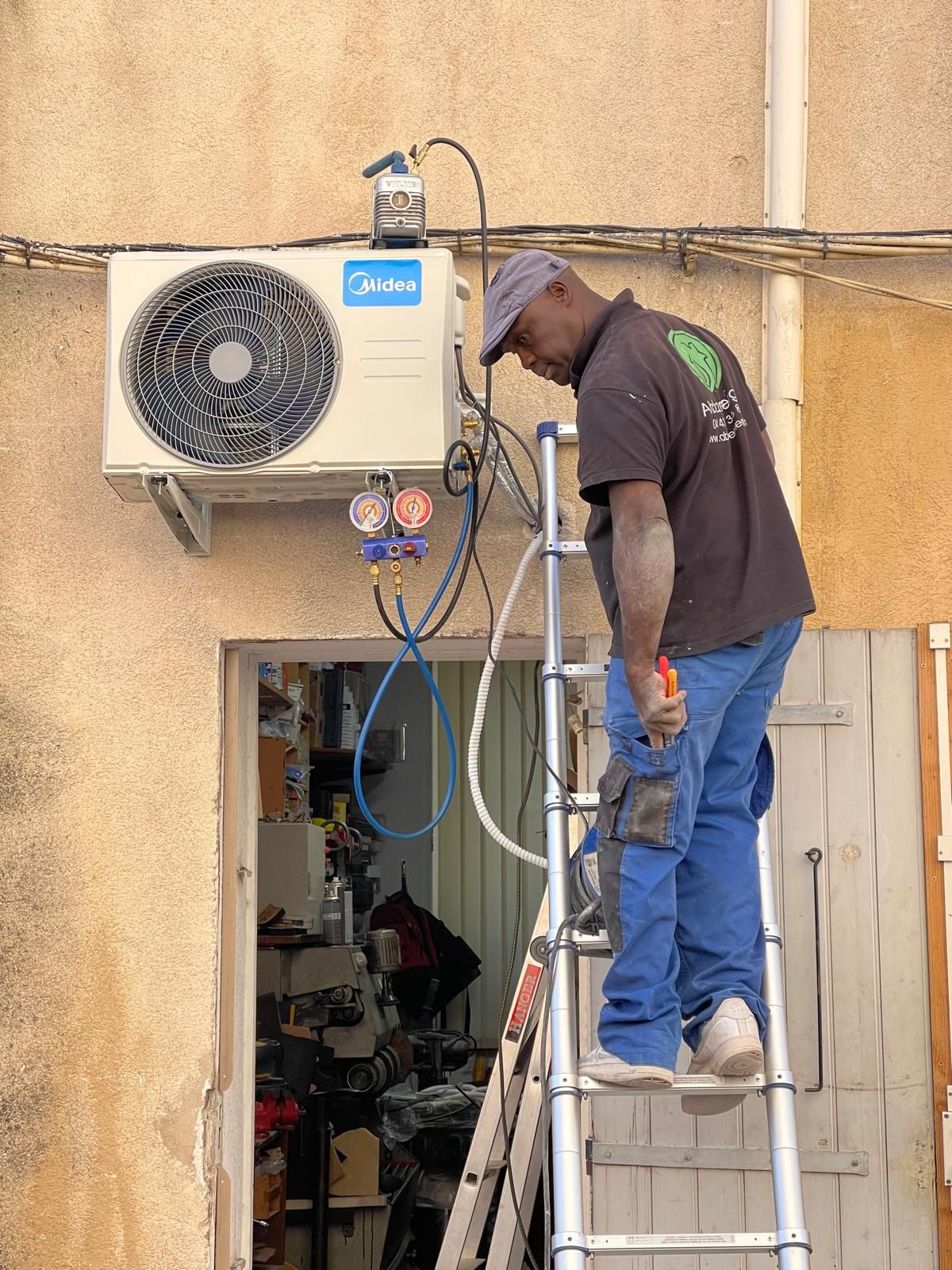 Main tenant une télécommande blanche pointée vers un climatiseur mural. La télécommande affiche la température.