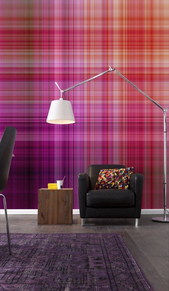 Wohnzimmer mit karierter Wand, schwarzem Sessel, Stehlampe, kleinem Tisch und lila Teppich.