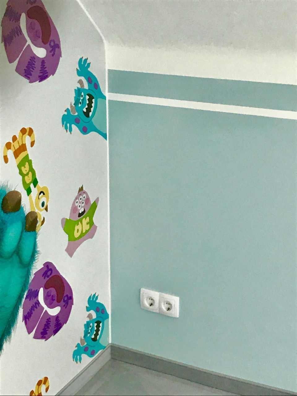 Wand mit Monsteraufklebern, hellblauer Farbe und Steckdosen.