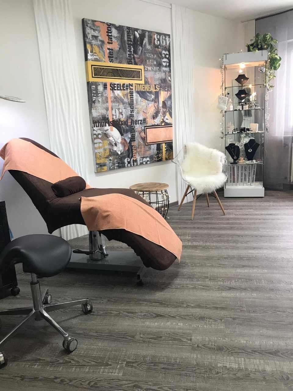 Saloneinrichtung: Massagestuhl mit Handtuch, Hocker, Kunstwerk.