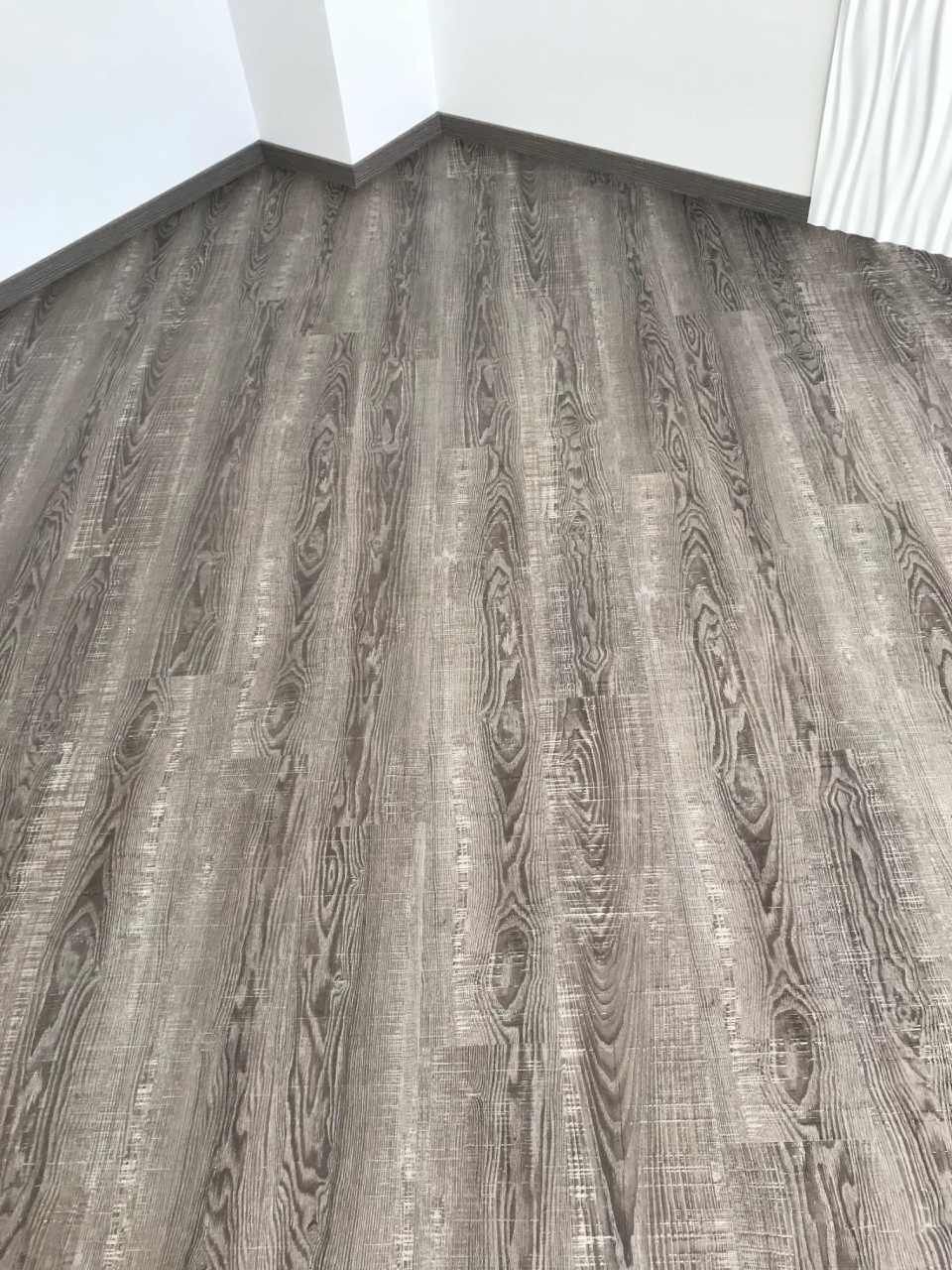 In einem Raum ist ein grauer Boden in Holzoptik verlegt.