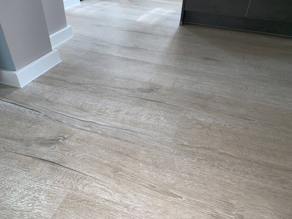 Heller Bodenbelag in Holzoptik mit grau-beigen Tönen.