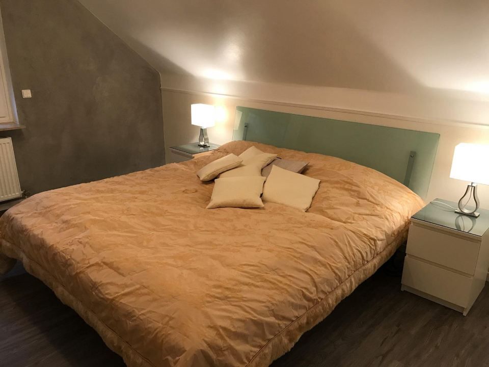 Schlafzimmer mit einem Bett, Nachttischen, Lampen und einem hellblaugrünen Kopfteil.