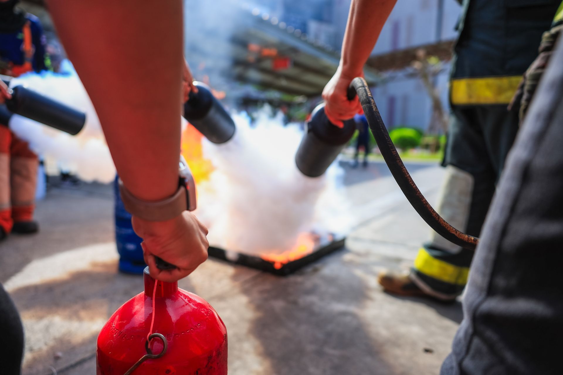 Des personnes utilisent des extincteurs pour éteindre un incendie dans une rue de la ville.