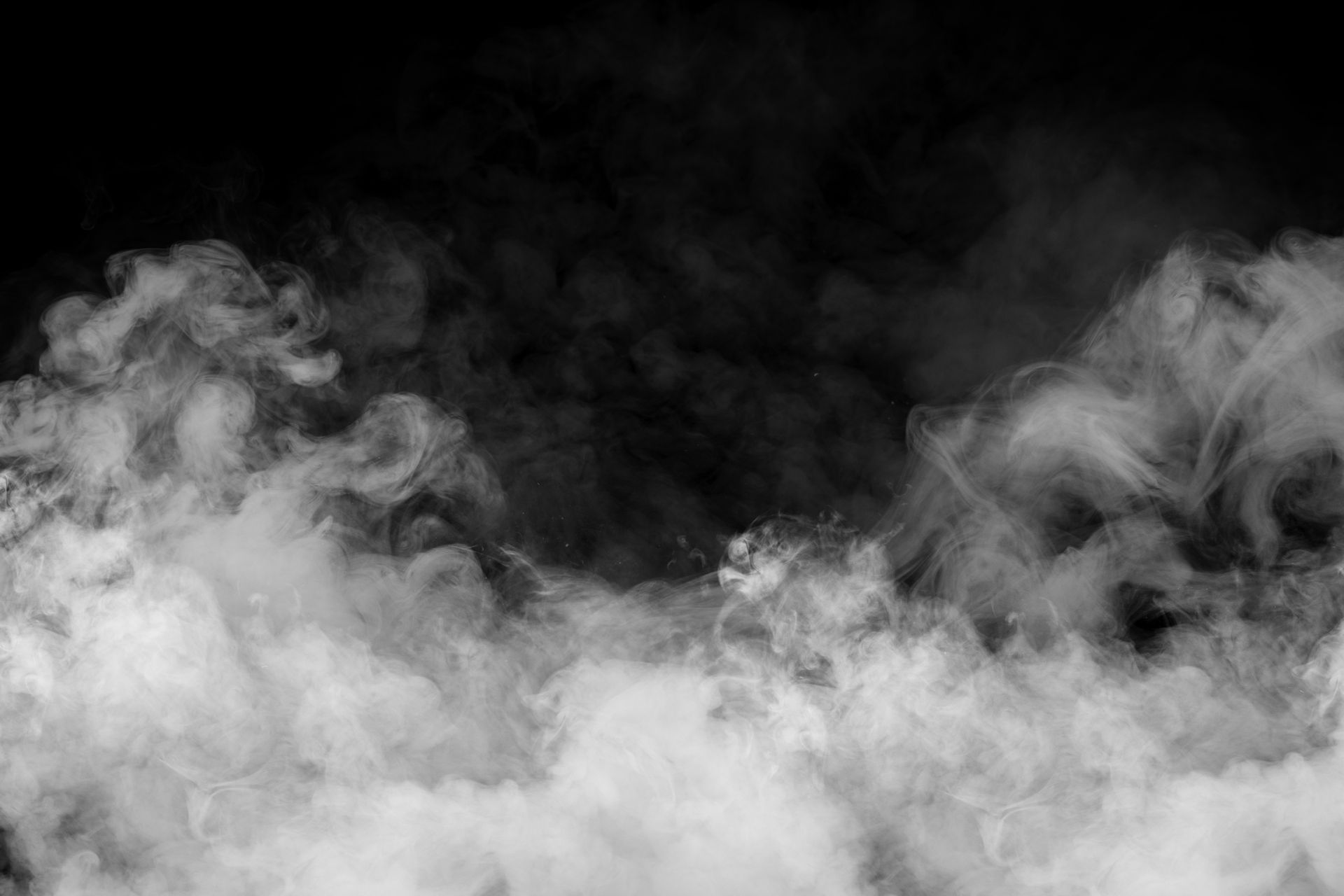 Fumée blanche ou brouillard dérivant sur un fond sombre.