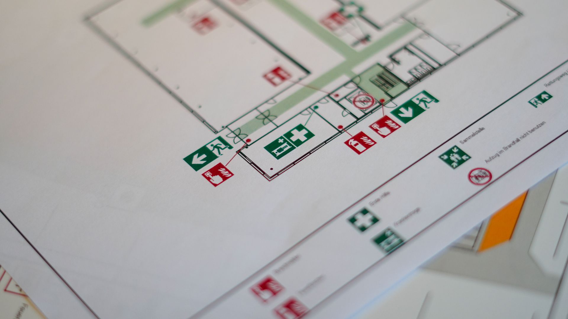 Plans d'étage imprimés avec symboles de sécurité rouges et verts sur un bureau.