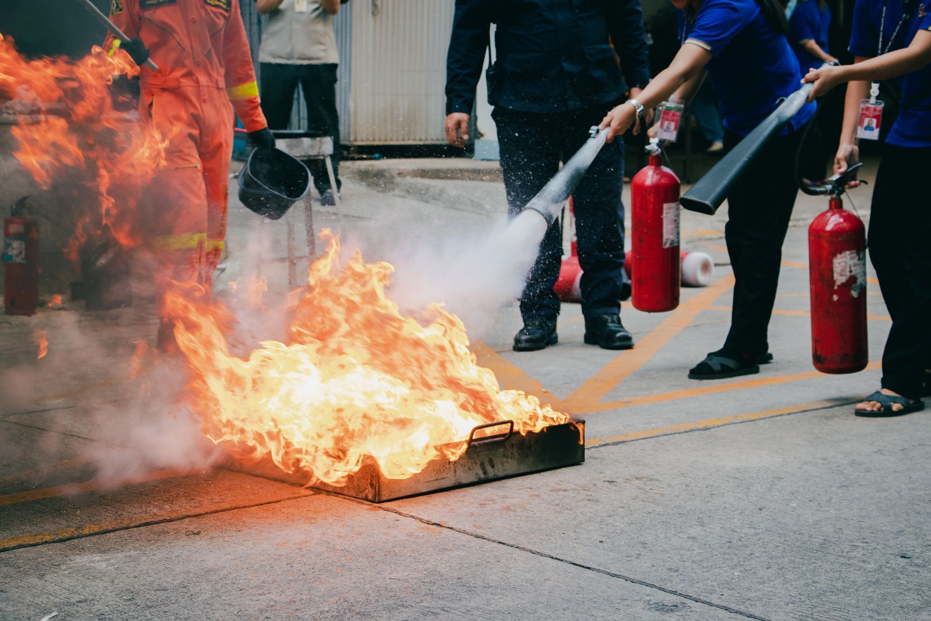 Des pompiers utilisent des extincteurs pour éteindre un incendie dans la rue.