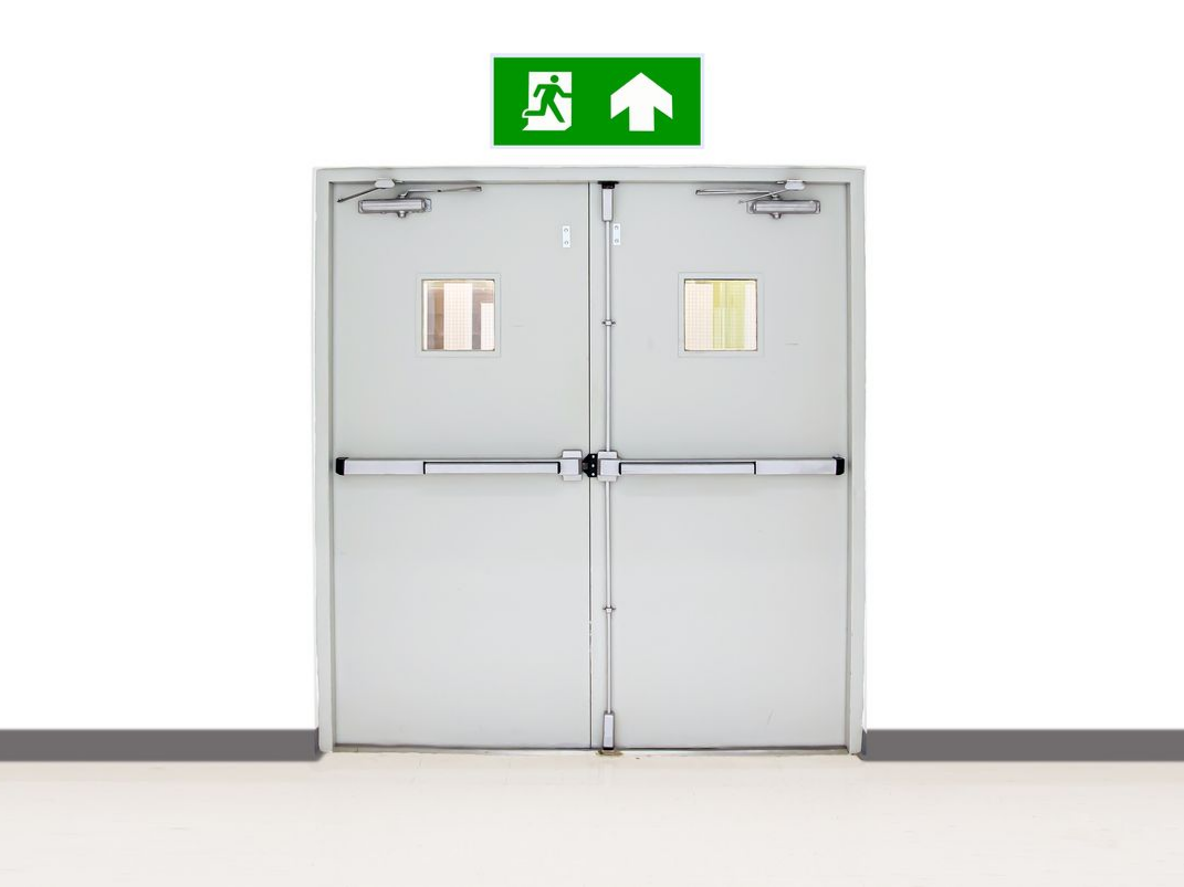 Double porte de sortie de secours avec panneau de sortie vert au-dessus, sur un mur blanc.