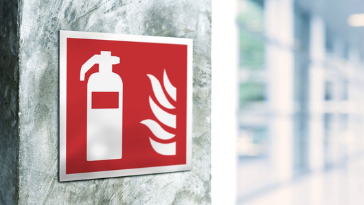 Panneau de sécurité rouge d'extincteur sur un mur près d'une fenêtre.