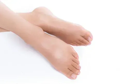 Pies descalzos, de piel clara, apoyados sobre una superficie blanca.