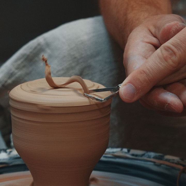 Una persona está trabajando en una olla de barro en un torno de alfarero.