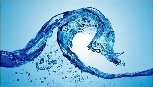 Una ola de agua azul en movimiento, con gotas y destellos capturados sobre un fondo azul claro.