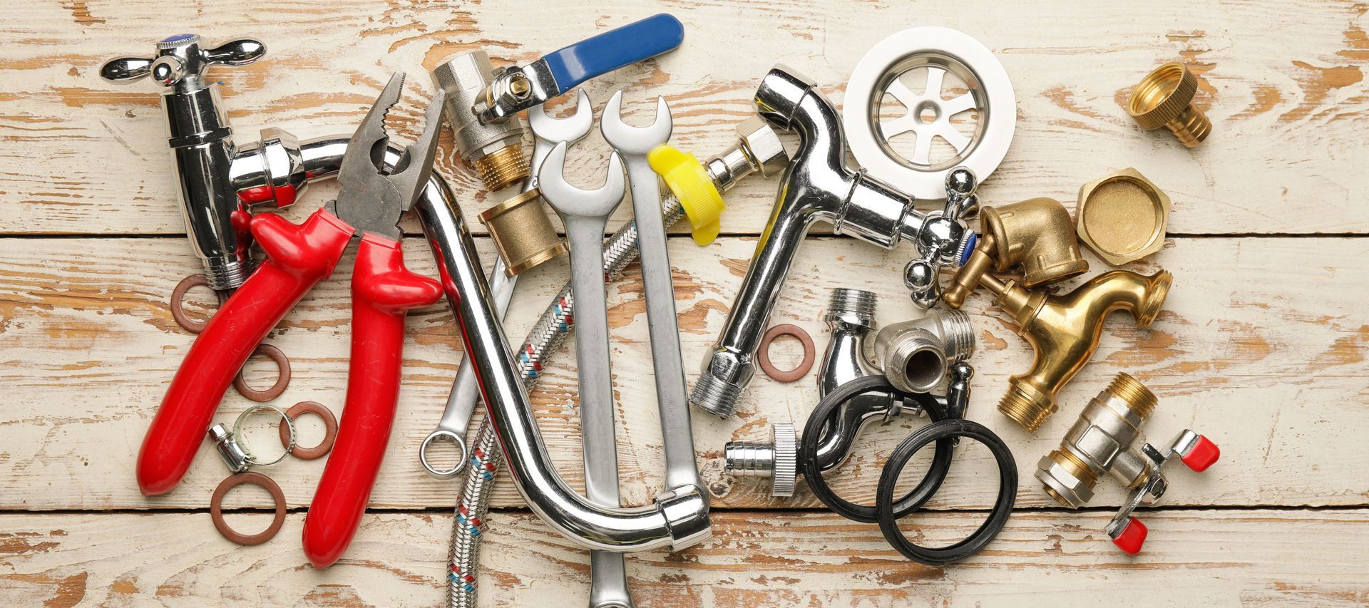 Pinces, serre-joints et petits outils divers étalés sur un établi en bois.