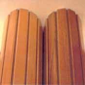 Dos paneles redondeados de madera de color marrón claro con ranuras verticales estriadas, colocados uno al lado del otro contra una pared beige.