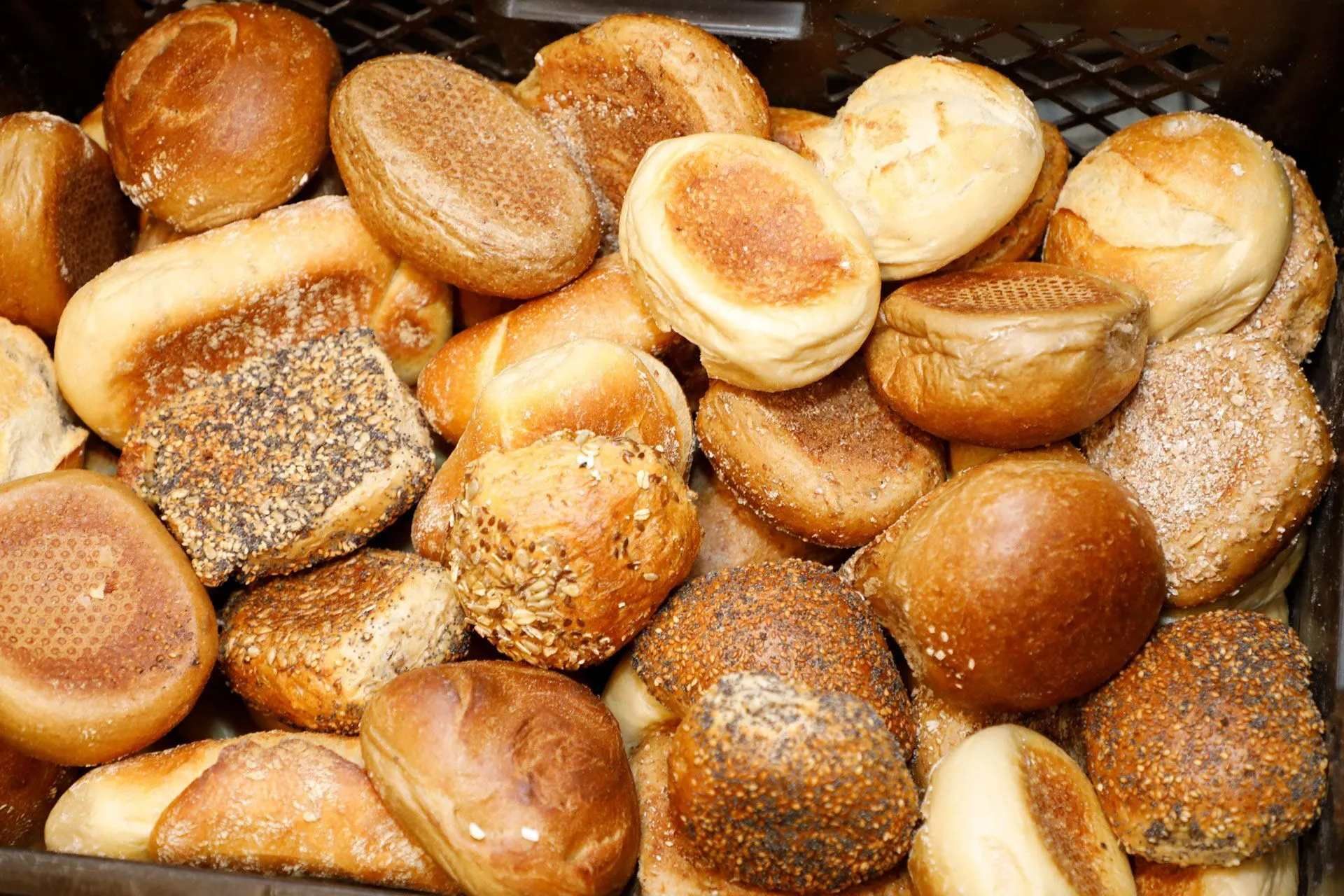 Gebackene Brötchen mit Zuckerstreuseln liegen auf einem mit Backpapier ausgelegten Backblech im Ofen.