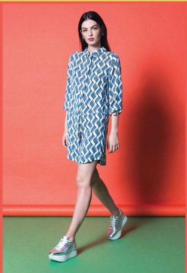 Una mujer lleva un vestido azul y blanco y zapatillas deportivas.