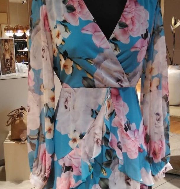 Un maniquí lleva un vestido floral azul y rosa.