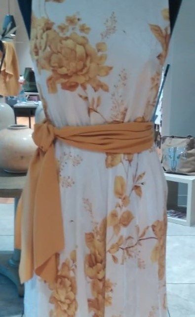 Un vestido blanco con flores amarillas está sobre un maniquí.
