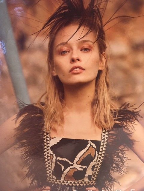 Una mujer con plumas en el pelo lleva un vestido negro.