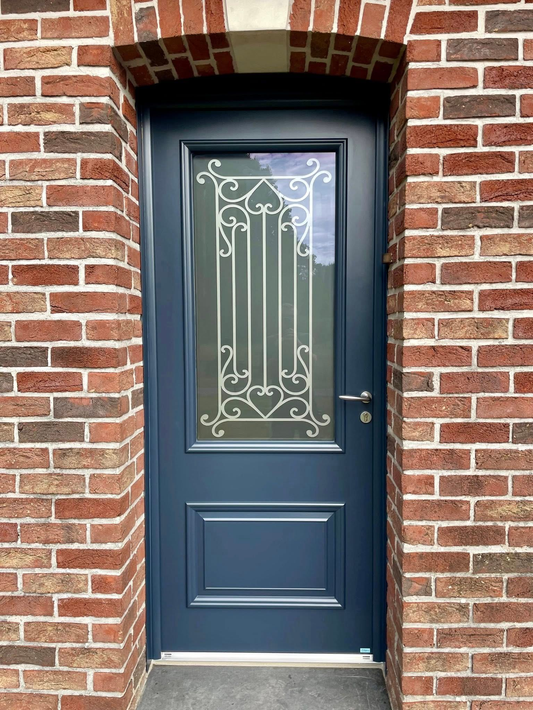 Porte bleue à vitre et ferronnerie décorative, encastrée dans un mur de briques.