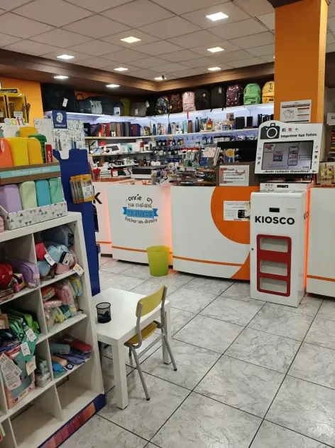 El interior de una tienda con estanterías llenas de material escolar, un mostrador 