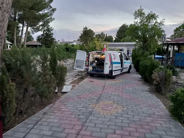 Una ambulancia está estacionada en un camino de entrada de ladrillo con las puertas abiertas.