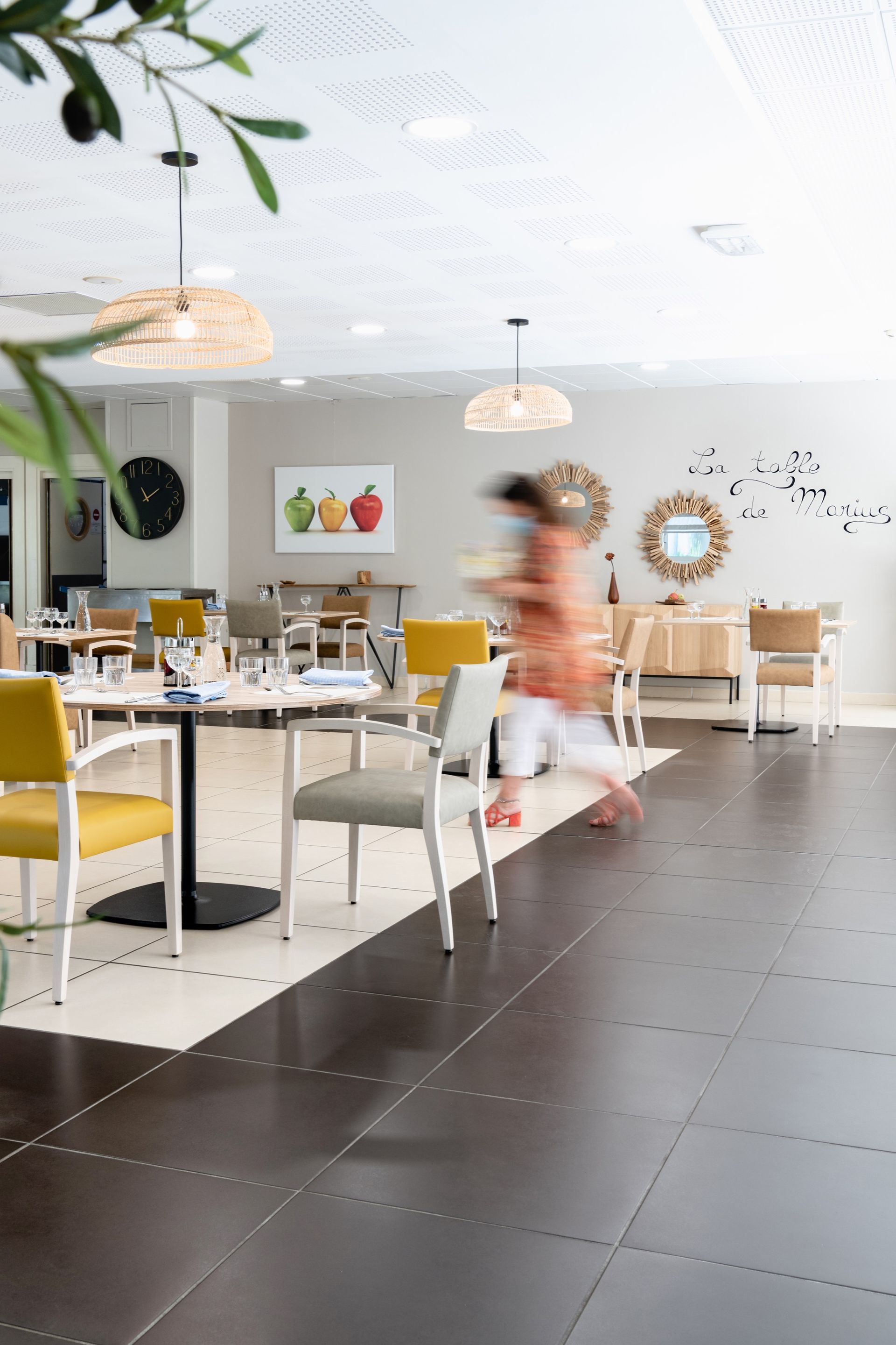 Salle à manger avec une personne floue courant devant des tables et des chaises.