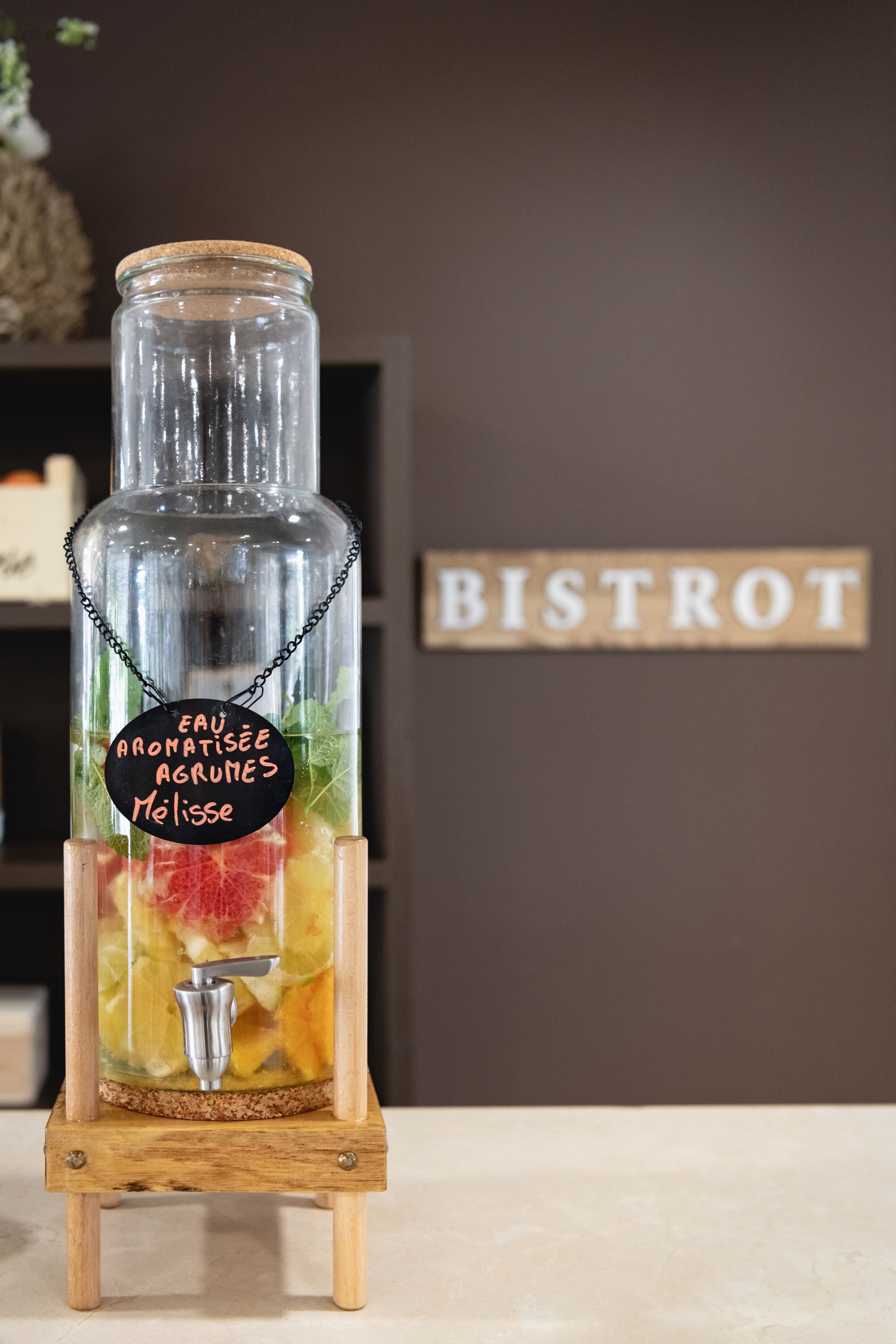 Distributeur de boissons en verre avec fruits, support en bois et enseigne
