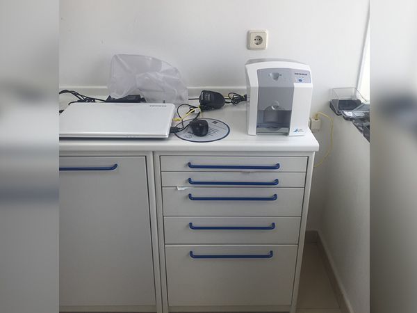 Un armario blanco con tiradores azules tiene una computadora portátil encima.