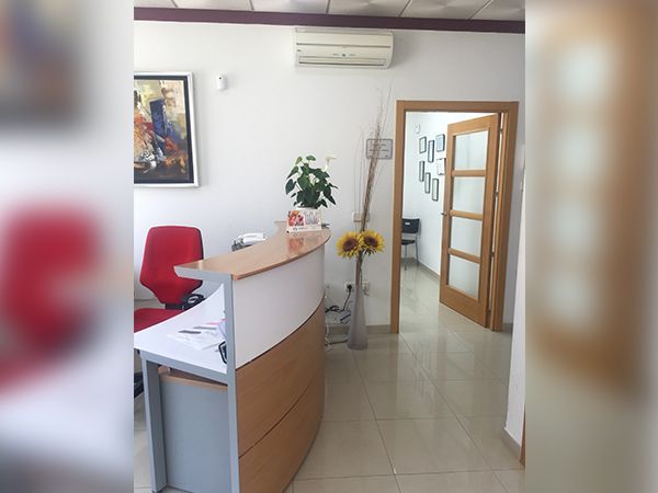 Un área de recepción con un escritorio y una silla roja.