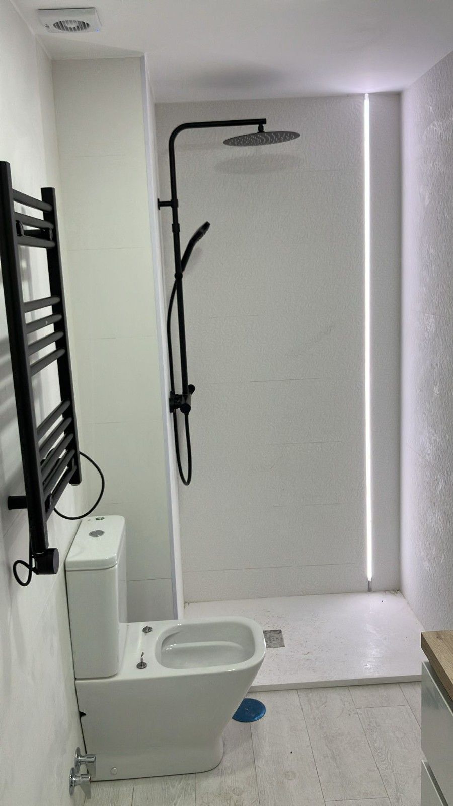 Habitación vacía con suelo de madera clara, paredes blancas, ventana divisoria con marco negro y una escalera a la derecha.