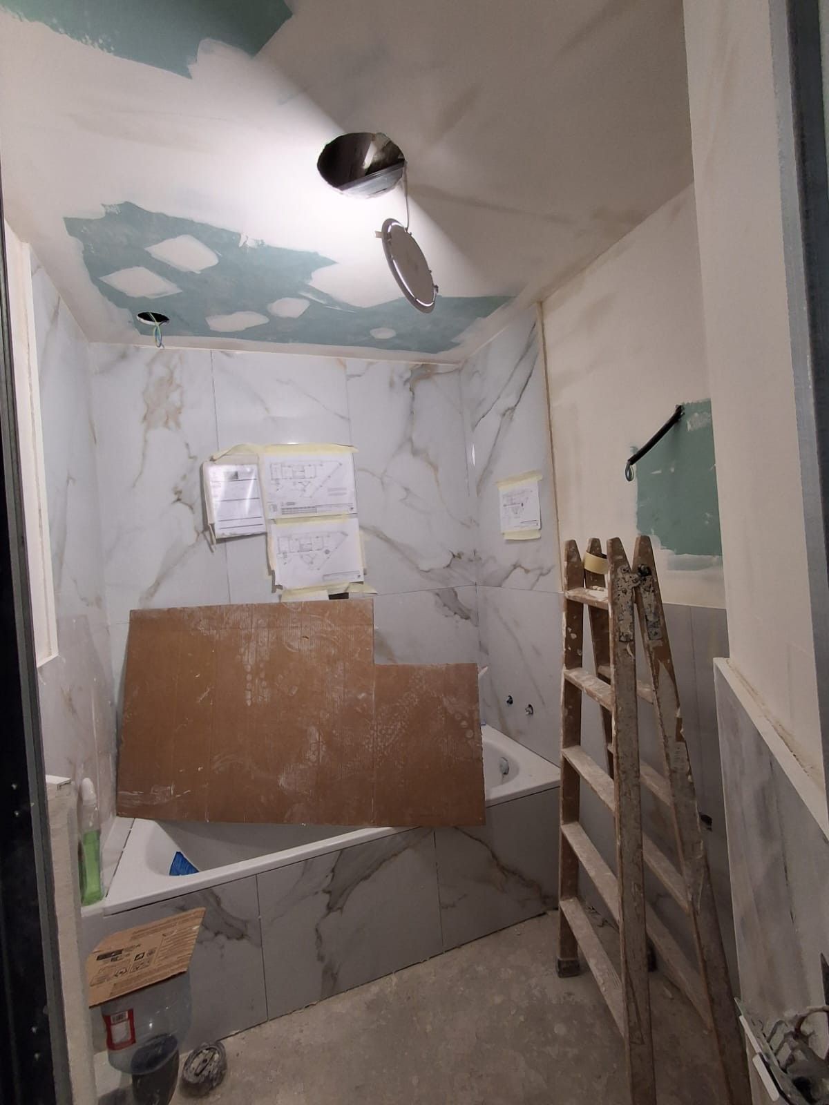 Pasillo estrecho sin terminar, con paredes enlucidas, ventana con luz