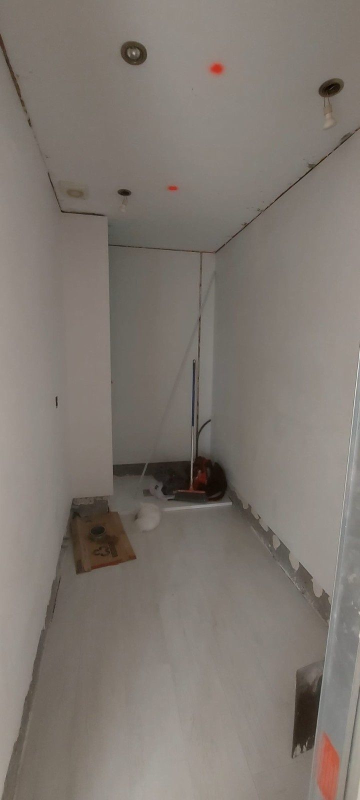 Habitación parcialmente terminada con paneles de yeso, materiales de construcción y una ventana en la parte trasera.