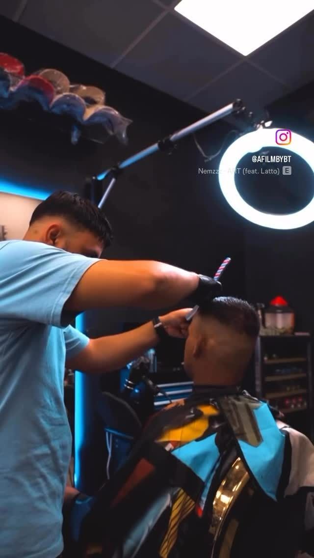 Barbero dando un corte de pelo en una tienda con un anillo de luz.