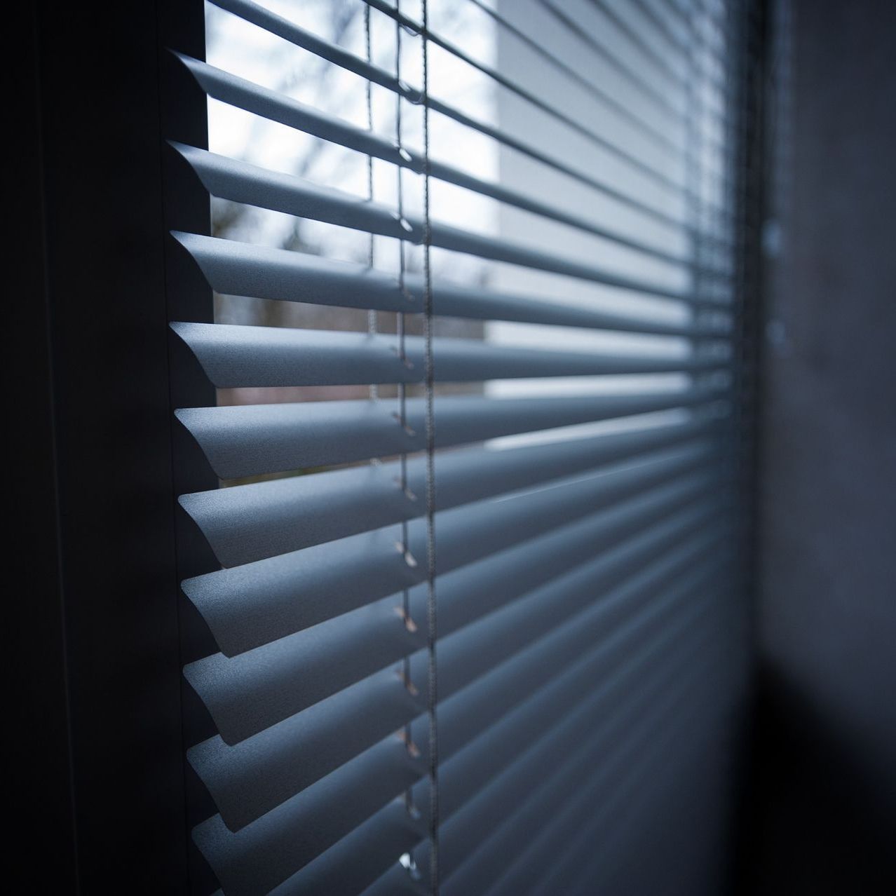 Una ventana con una persiana blanca en una pared de ladrillos