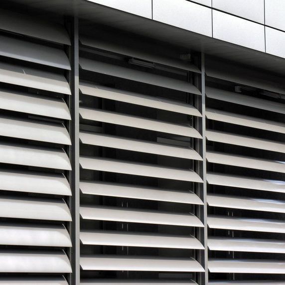 Una ventana con una persiana blanca en una pared de ladrillos