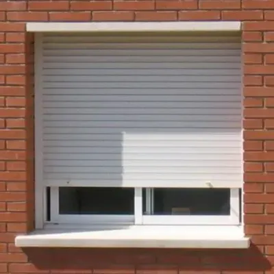 Una ventana con una persiana blanca en una pared de ladrillos