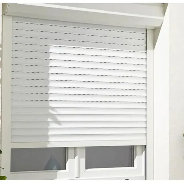 Una ventana con una persiana blanca en una pared de ladrillos