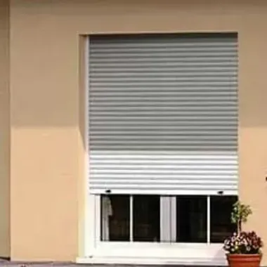 Una ventana con una persiana y una planta en maceta delante de ella.