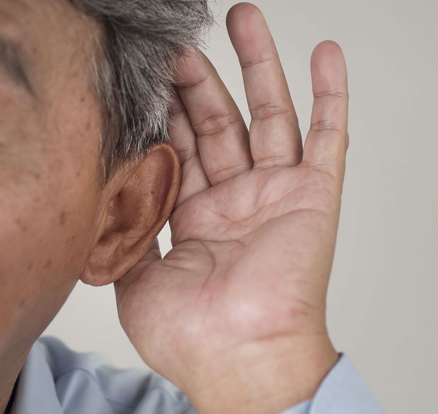 Un hombre se lleva la mano a la oreja para escuchar algo.