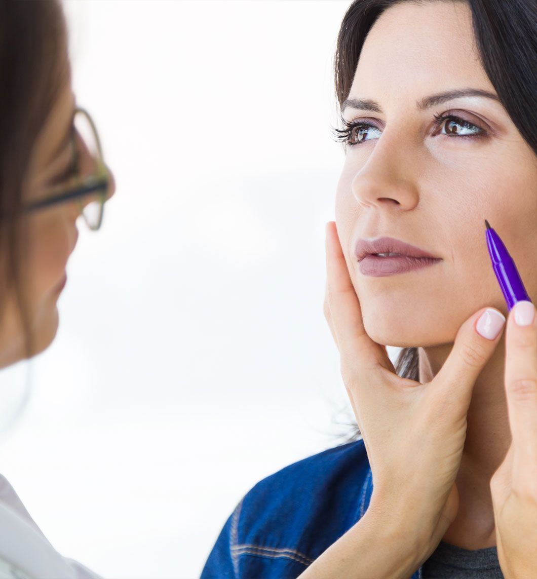 Un médico marca el rostro de una mujer con un bolígrafo durante una consulta.