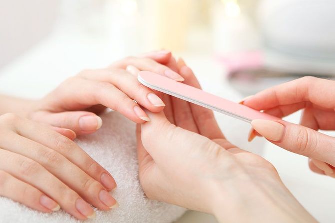 Eine Frau lässt sich von einer Nageldesignerin die Nägel machen.