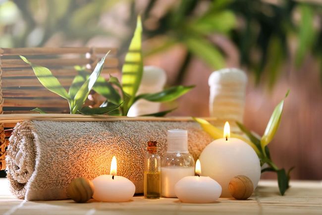 Ein Handtuch, Kerzen, ätherische Öle und Steine auf einem Tisch in einem Spa.