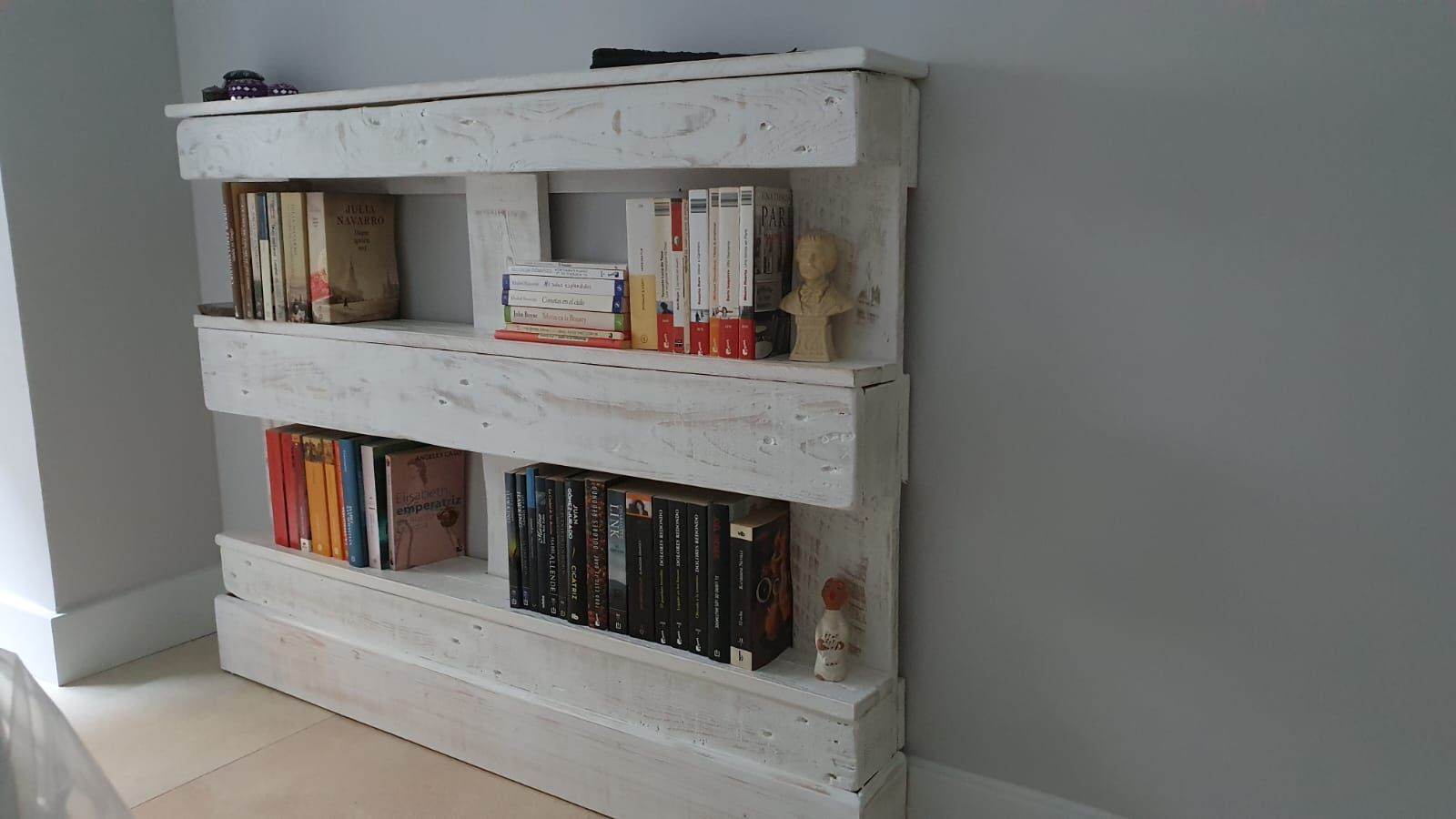 Una estantería de madera blanca llena de libros en una habitación.