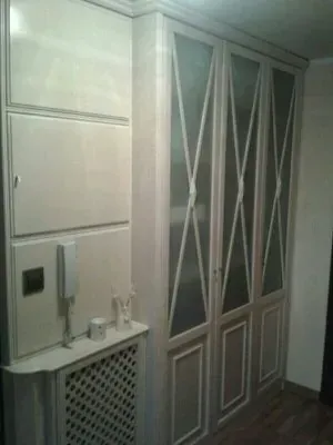 Un pasillo con armarios blancos y una cubierta de radiador.