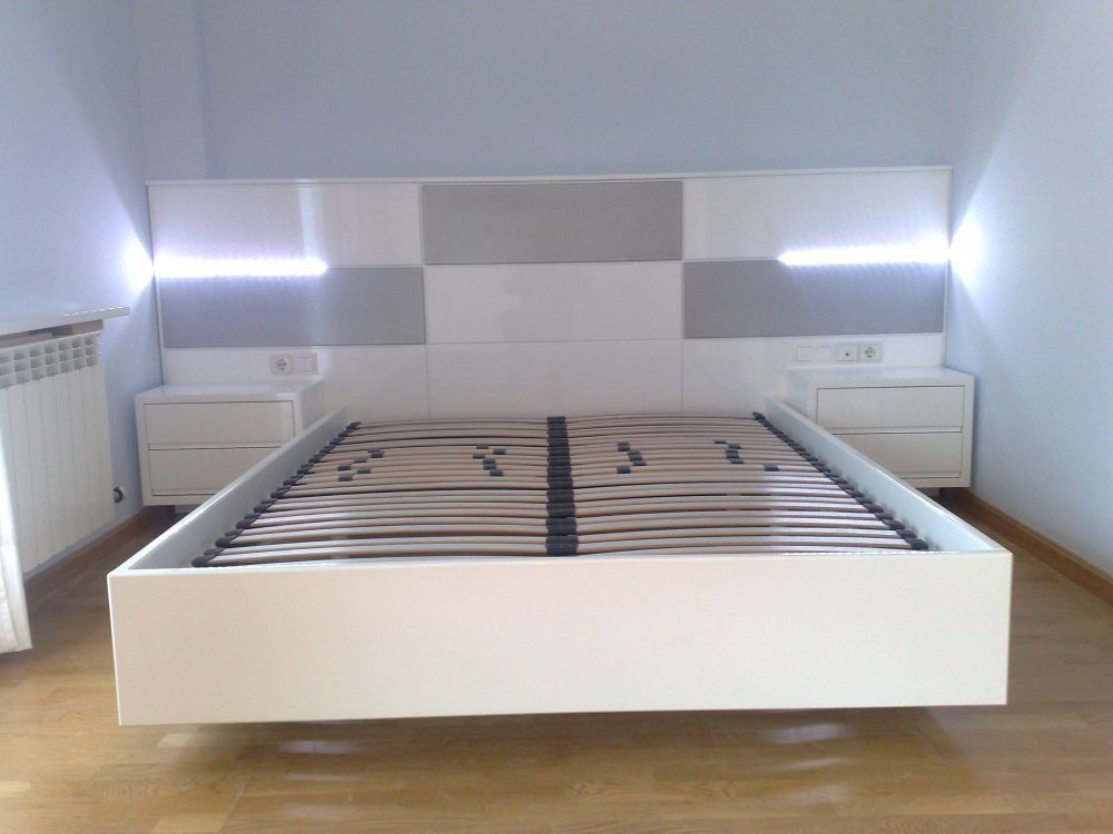 Un dormitorio con una cama blanca y dos mesitas de noche.